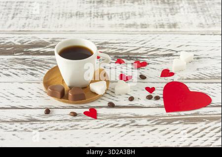 Composition festive de la St Valentin. Café noir romatique avec du sucre en sashape de coeur et confettis de coeur en papier dispersé rouge Banque D'Images