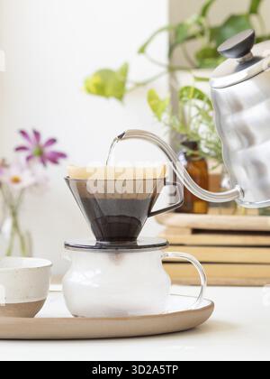 L'eau chaude étant versée d'une bouilloire moderne dans un filtre à café, préparant une tasse de café fraîche Banque D'Images