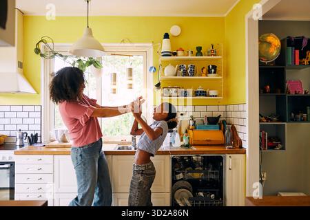 Mère et fille insouciantes jouant dans la cuisine à la maison Banque D'Images