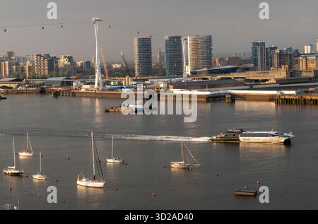Un Uber Boat Thames Clipper, un service de bus sur la Tamise, passe sous le téléphérique de Londres qui traverse la Tamise et amarré des bateaux de plaisance lorsqu'il passe devant la péninsule de Greenwich en direction de l'est à Londres, Royaume-Uni, le 15 avril 2023. Crédit : Rob Taggart/Alamy Banque D'Images