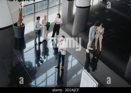 Collègues et professionnels se réunissent dans un hall de bureau moderne pour une réunion collaborative Banque D'Images