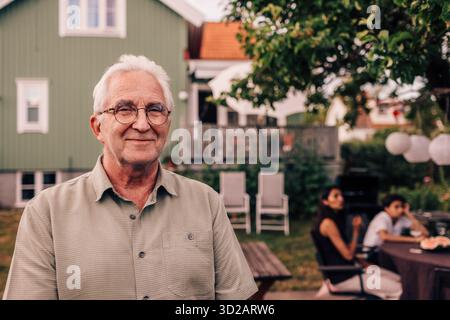 Portrait d'un homme âgé souriant portant des lunettes à la fête de cour arrière Banque D'Images