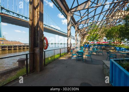 Un pont enjambe une rivière avec un sauveteur sur la balustrade. Le pont est entouré d'un parc avec tables et chaises. Cherry Street Pier Banque D'Images