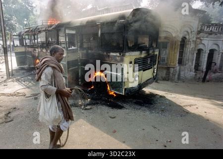 Un Indien passe devant un bus incendié par de violents manifestants nationalistes hindous qui se sont révoltés sur le site religieux contesté, le 30 octobre 1990 à Ayodhya, en Inde. La mosquée Babri Masjid du XVIe siècle est revendiquée comme le lieu de naissance du Seigneur Ram dans la mythologie hindoue. Banque D'Images