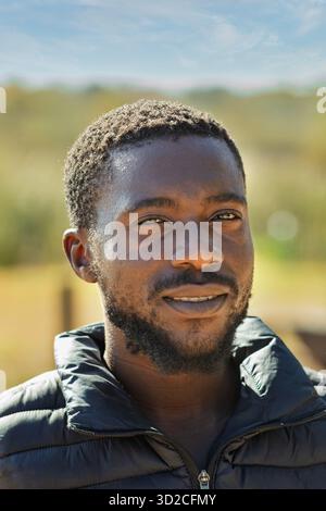 portrait de jeune homme africain souriant, tête et épaules, plein air, nature Banque D'Images