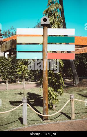 Maquette colorée de panneau vertical en bois vierge dans le cadre d'un parc extérieur, avec des panneaux directionnels vides dans des tons pastel idéal pour le texte ou la marque temp Banque D'Images