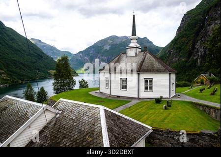 Vacances dans le sud de la Norvège : le fjord épique de Geiranger - la belle vieille église de Geiranger avec cimetière et vue sur le fjord Banque D'Images