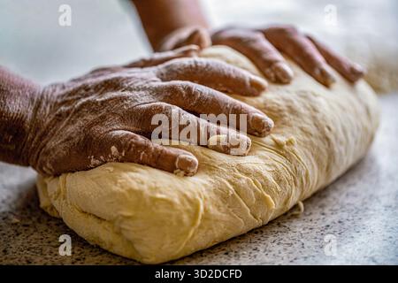 Faire de la pâte par des mains masculines à la boulangerie. Concept alimentaire. Pâte à main. Mains féminines fabriquant de la pâte pour pizza. Chef dans la cuisine professionnelle prépare la pâte Banque D'Images