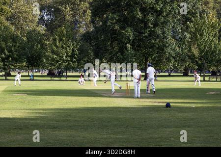 Match de cricket amateur dans un parc verdoyant de la ville avec des joueurs Banque D'Images