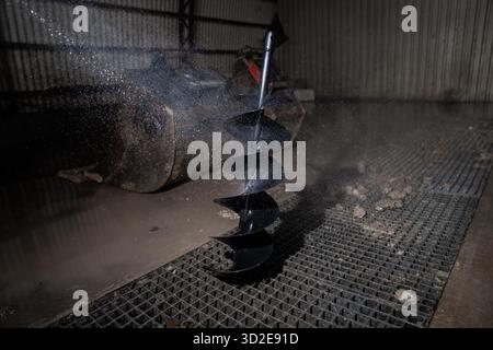 Le foret à vis sans fin en acier noir de nettoyage à l'eau haute pression élimine les résidus de terre et les débris de la surface de la lame en spirale dans l'atelier de construction pour l'entretien Banque D'Images