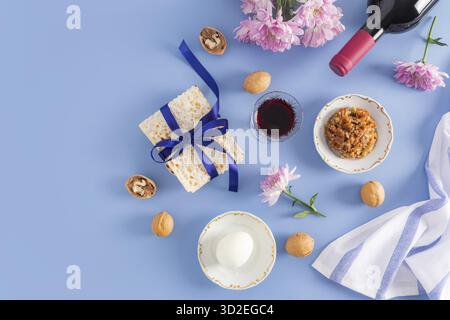 Magnifique fond bleu de la Pâque de la Pâque juive. vue de dessus d'une bouteille de vin casher rouge, verres de vin, matzah, noix, oeuf sur une assiette Banque D'Images