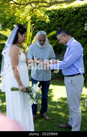 Échanger des bagues, mariée et mariée dans la cérémonie de jardin avec officiant présent. mariage senior, mariage, vœux, célébration, à l'extérieur, union || autorisation du modèle Banque D'Images