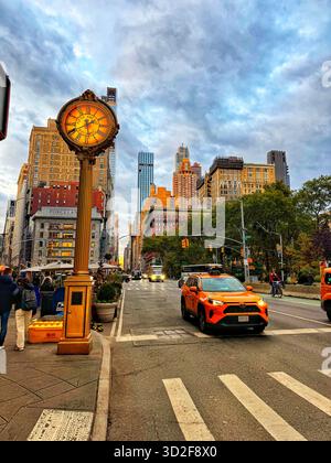 Lumière dorée du soir sur la Cinquième Avenue près du Flatiron Building, New York City, avec horloge de rue vintage et taxis jaunes. Banque D'Images