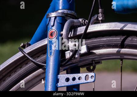 Gros plan d'une roue avant de vélo bleu vintage, d'un système de freinage et de détails de cadre à la lumière du soleil. Banque D'Images