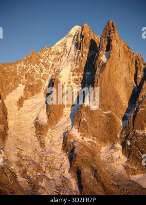 VUE AÉRIENNE. Face rocheuse vertigineuse des Drus (3754m) au coucher du soleil. Au loin, aiguille verte enneigée (4122m). Chamonix, haute-Savoie, France. Banque D'Images