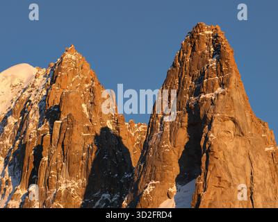 VUE AÉRIENNE. Le Dru avec ses falaises incroyablement vertigineuses. Vue du sud-ouest, son granit ferrugineux brille au coucher du soleil. MT Blanc, France. Banque D'Images