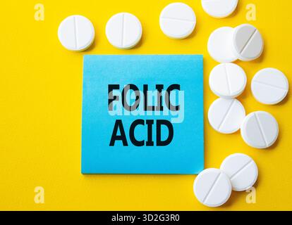Symbole d'acide folique. Mot concept acide folique sur note bleue. Beau fond jaune avec des pilules. Médecine et concept d'acide folique. Copier l'espace Banque D'Images