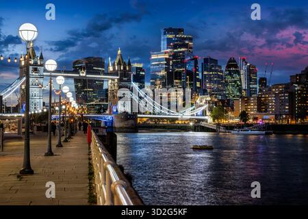 Belle vue en soirée depuis la passerelle de la Tamise jusqu'au Tower Bridge illuminé et à la ville de Londres, en Angleterre Banque D'Images