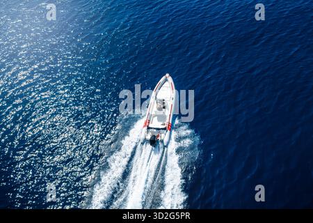 Vue aérienne d'un bateau à moteur RIB qui survole l'océan bleu étincelant Banque D'Images