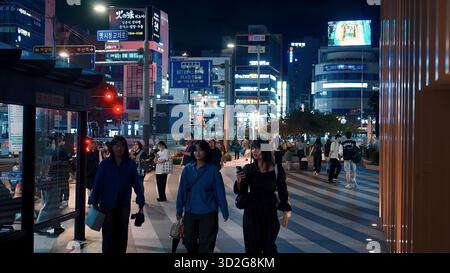 BUSAN, CORÉE DU SUD - 10 OCTOBRE. 2025 - les gens marchant dans une rue de la ville la nuit avec des panneaux au néon et des lumières urbaines Banque D'Images