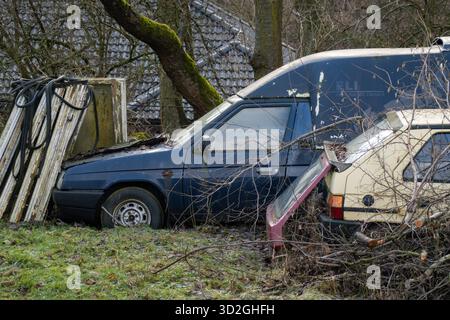 Petrvald, Tchéquie - 26 janvier 2024 : épave de voitures Skoda Favorit jaunes et bleues garées dans la brousse Banque D'Images