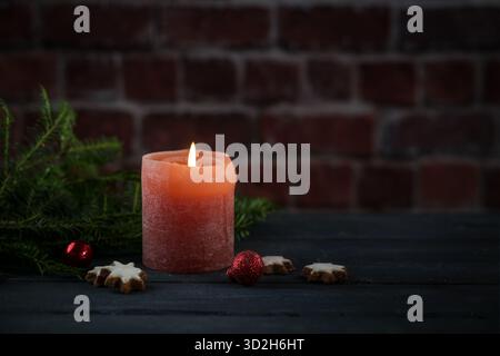 Bougie rouge et quelques décorations de Noël contre un mur de briques, lumière dans le noir pour Noël, Avent ou nouvel an, espace copie, Focus sélectionné, narro Banque D'Images