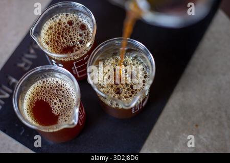 Focus sélectif café noir dans un verre transparent verser le café d'un pichet en verre dans un verre à mesurer transparent avec des chiffres indiquant la quantité sur t Banque D'Images
