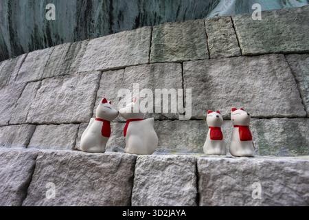 Adorables figurines d'ours polaire blanc avec des foulards rouges vifs se tiennent ensemble mur de pierre robuste. charmante scène familiale de vacances d'hiver, mignon décoratif Banque D'Images