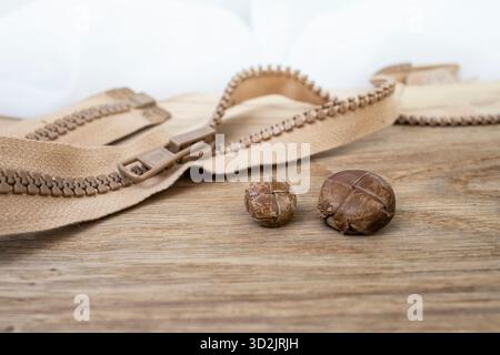 Boutons en cuir vintage et fermeture éclair sur fond de bureau en bois de chêne brun, soft focus close up, nature morte Banque D'Images