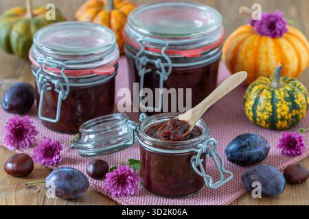 confiture de prunes dans des pots de conservation avec plateau pivotant, prunes fraîches et citrouille sur la table Banque D'Images
