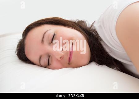 Photo d'une jeune femme dormant dans son lit avec un fond blanc Banque D'Images