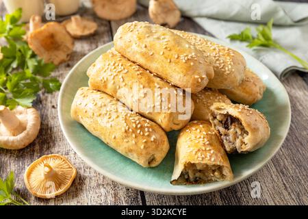 Pâtisseries aux champignons salées maison avec graines de sésame sur table rustique en bois. Banque D'Images