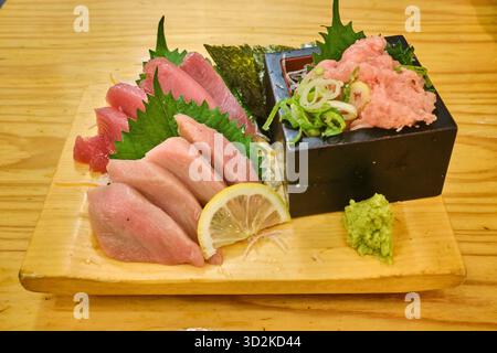 Une variété de sashimi de thon frais magnifiquement disposés sur une assiette geta traditionnelle en bois Banque D'Images