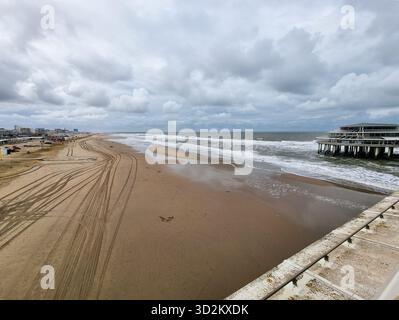 Plage de sable presque vide de Scheveningen en mer du Nord un jour d'automne ; avec quelques pistes de voiture dans le sable ; vu de la jetée, qui est partiellement visible Banque D'Images