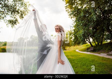 Mariée heureuse et mariée le jour du mariage, soulevant long voile de mariée || modèle libéré Banque D'Images