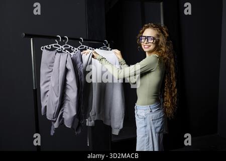 Jeune femme choisissant des vêtements à la cabine d'essayage. Concept de shopping Banque D'Images
