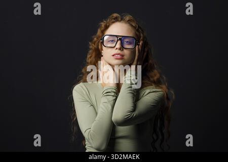 Jeune femme aux cheveux rouges portant des lunettes regardant la caméra avec un sourire joyeux Banque D'Images