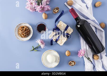 Magnifique fond bleu de la Pâque de la Pâque juive. vue de dessus d'une bouteille de vin casher rouge, verres de vin, matzah, noix, oeuf sur une assiette Banque D'Images