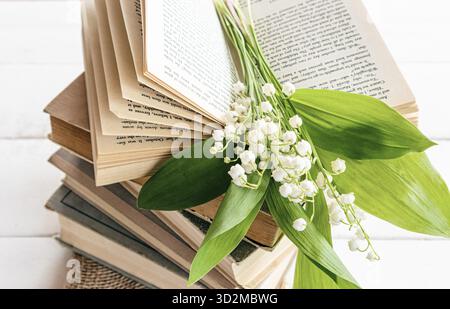 Une pile de vieux livres et un bouquet de lis printaniers de la vallée sur un livre ouvert. vue de face. composition de printemps avec des fleurs. bonne humeur du matin Banque D'Images