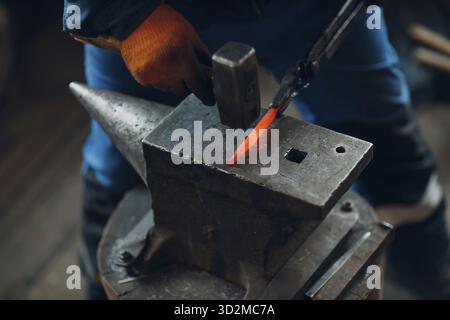 Forge forge et fait des détails en métal avec un marteau et une enclume à la forge Banque D'Images