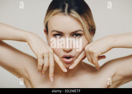 Femme faisant des massages de yoga du visage et des exercices rajeunissants facebuilding avec ses mains Banque D'Images