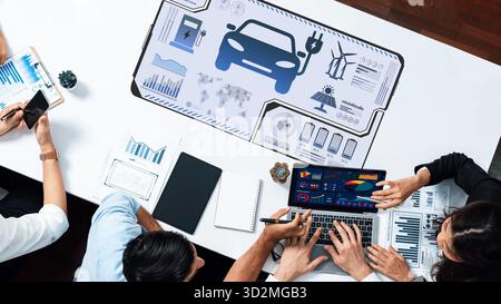 Groupe de professionnels collaborant à l'innovation automobile en utilisant des outils d'analyse numérique et de visualisation de données dans un environnement de bureau moderne, highlig Banque D'Images