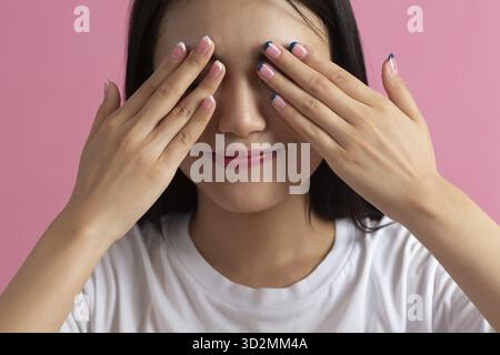 Gros plan portrait d'une jeune femme asiatique avec main paume doigts ongles manucure yeux fermés visage Banque D'Images