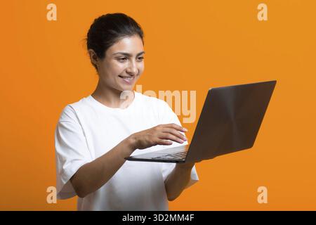 Portrait d'une jeune femme indienne souriante travaillant avec un ordinateur portable Banque D'Images