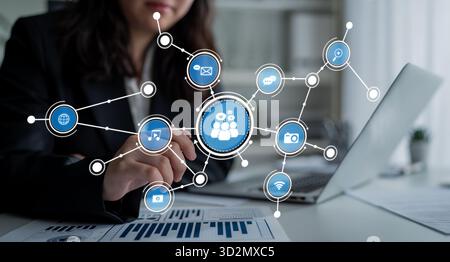 Une femme d'affaires interagit avec un ordinateur portable, présentant un concept dynamique de réseau de médias sociaux avec des icônes représentant divers canaux de communication et Banque D'Images