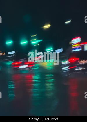 Vue artistique des voitures en mouvement et des lumières de la ville à travers des gouttes de pluie sur un pare-brise pendant une nuit pluvieuse à Edmonton, Alberta, Canada Banque D'Images