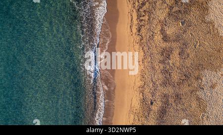Drone vue aérienne de dessus du littoral méditerranéen où la mer turquoise rencontre le sable doré, symétrie naturelle parfaite des vagues et de la plage. Banque D'Images