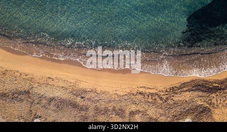 Drone vue aérienne de dessus du littoral méditerranéen où la mer turquoise rencontre le sable doré, symétrie naturelle parfaite des vagues et de la plage. Banque D'Images