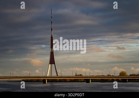Riga TV Tower s'élevant au-dessus de la rivière Daugava sous des nuages spectaculaires représentant un monument emblématique letton, une structure d'ingénierie architecturale et moderne Banque D'Images