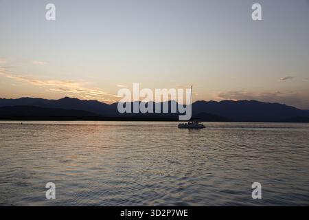 Port Douglas, Queensland, Australie 3 octobre 2025 Yacht dérive paresseusement à travers l'entrée du port de Port Douglas alors que le soleil se couche sur la Mounta Banque D'Images